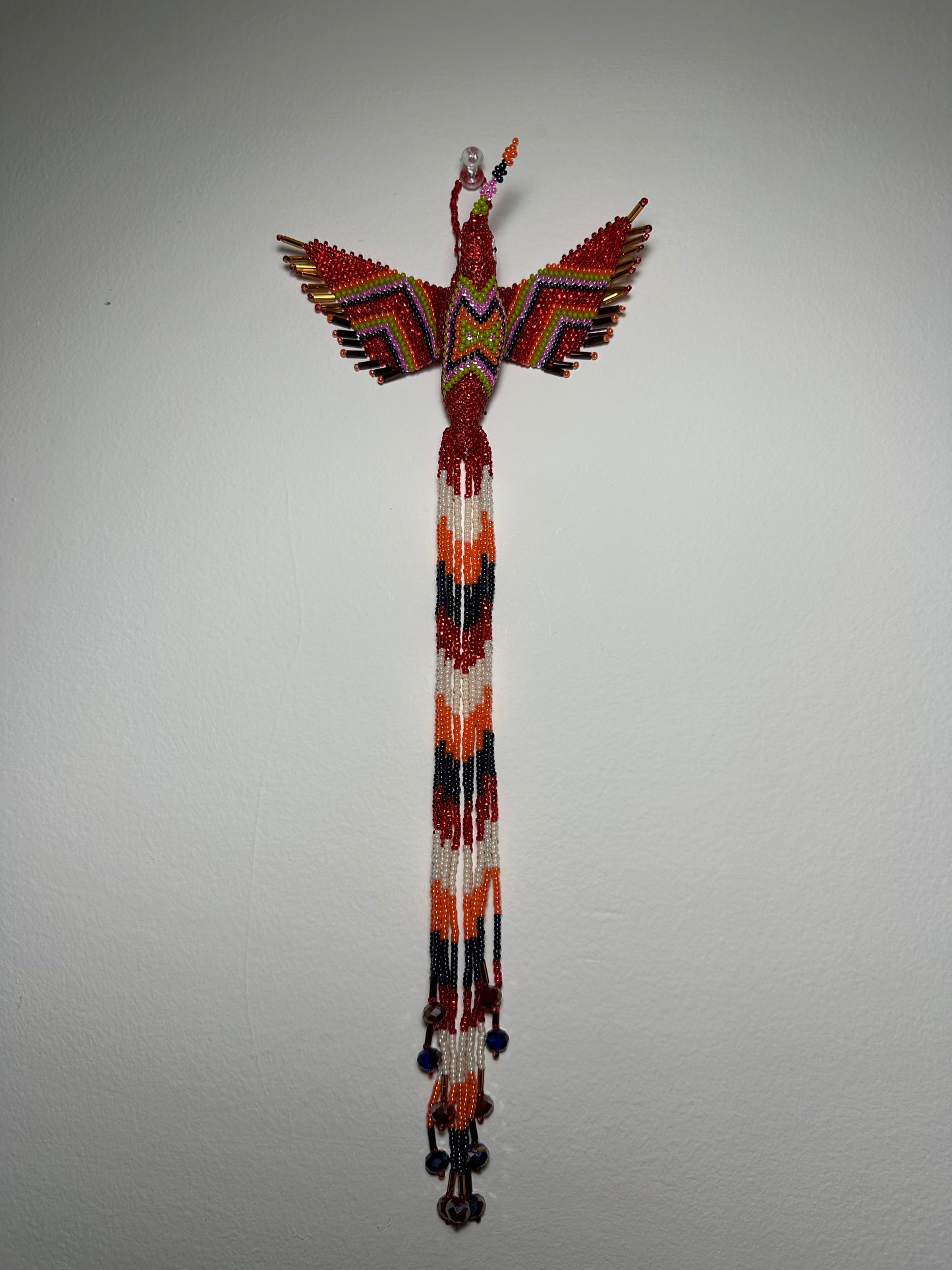 Show off your love of nature with this one-of-a-kind, handmade Guatemalan beaded hummingbird hanging ornament. This whimsical piece is sure to add a touch of joy to your home, garden, or patio. Perfect for those who appreciate unique and handmade designs, this piece is sure to become a treasured part of your space. Add a pop of color and a touch of whimsy to your home today with this beautiful hummingbird hanging ornament.