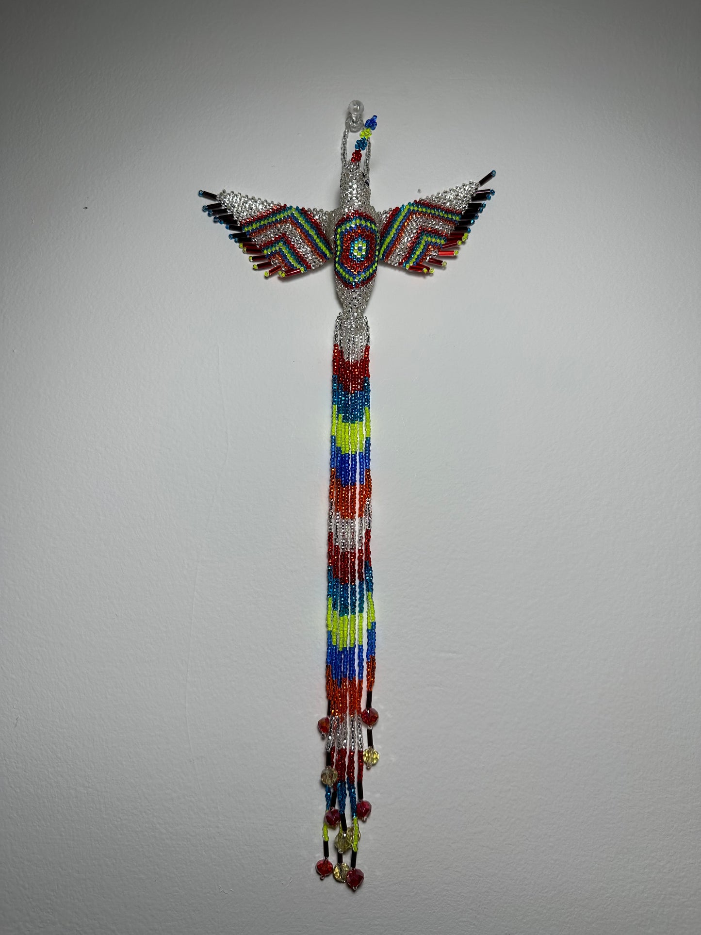 Show off your love of nature with this one-of-a-kind, handmade Guatemalan beaded hummingbird hanging ornament. This whimsical piece is sure to add a touch of joy to your home, garden, or patio. Perfect for those who appreciate unique and handmade designs, this piece is sure to become a treasured part of your space. Add a pop of color and a touch of whimsy to your home today with this beautiful hummingbird hanging ornament.