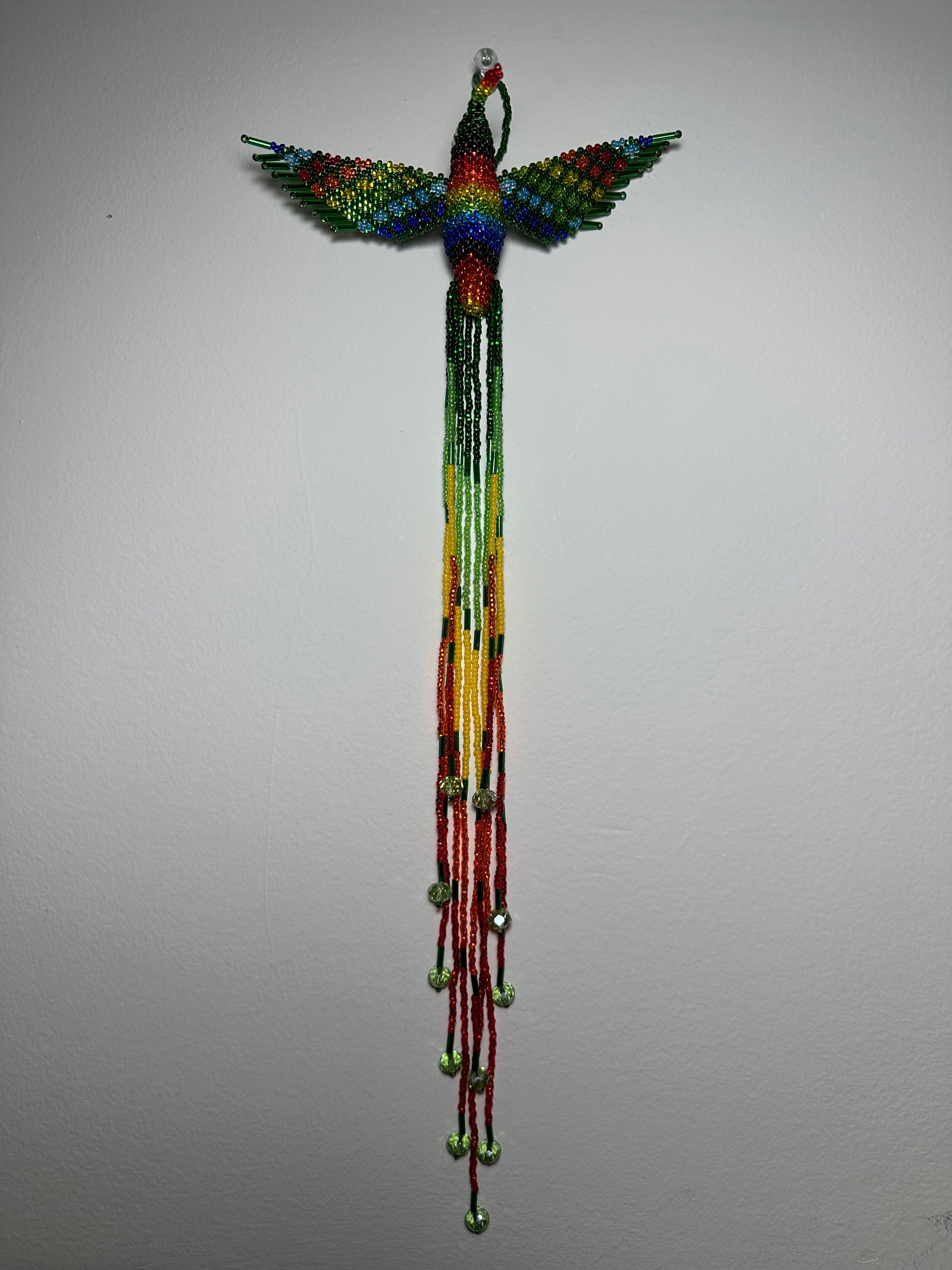 Show off your love of nature with this one-of-a-kind, handmade Guatemalan beaded hummingbird hanging ornament. This whimsical piece is sure to add a touch of joy to your home, garden, or patio. Perfect for those who appreciate unique and handmade designs, this piece is sure to become a treasured part of your space. Add a pop of color and a touch of whimsy to your home today with this beautiful hummingbird hanging ornament.