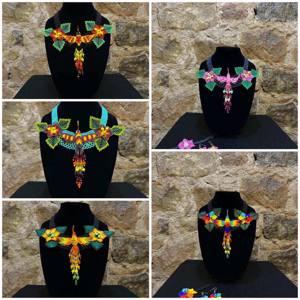 This vibrant hummingbird necklace and earring set are sure to bring a touch of cheerful color to any look. Expertly crafted, each set is made up of three-dimensional beading of flower set among three leaves with a 6